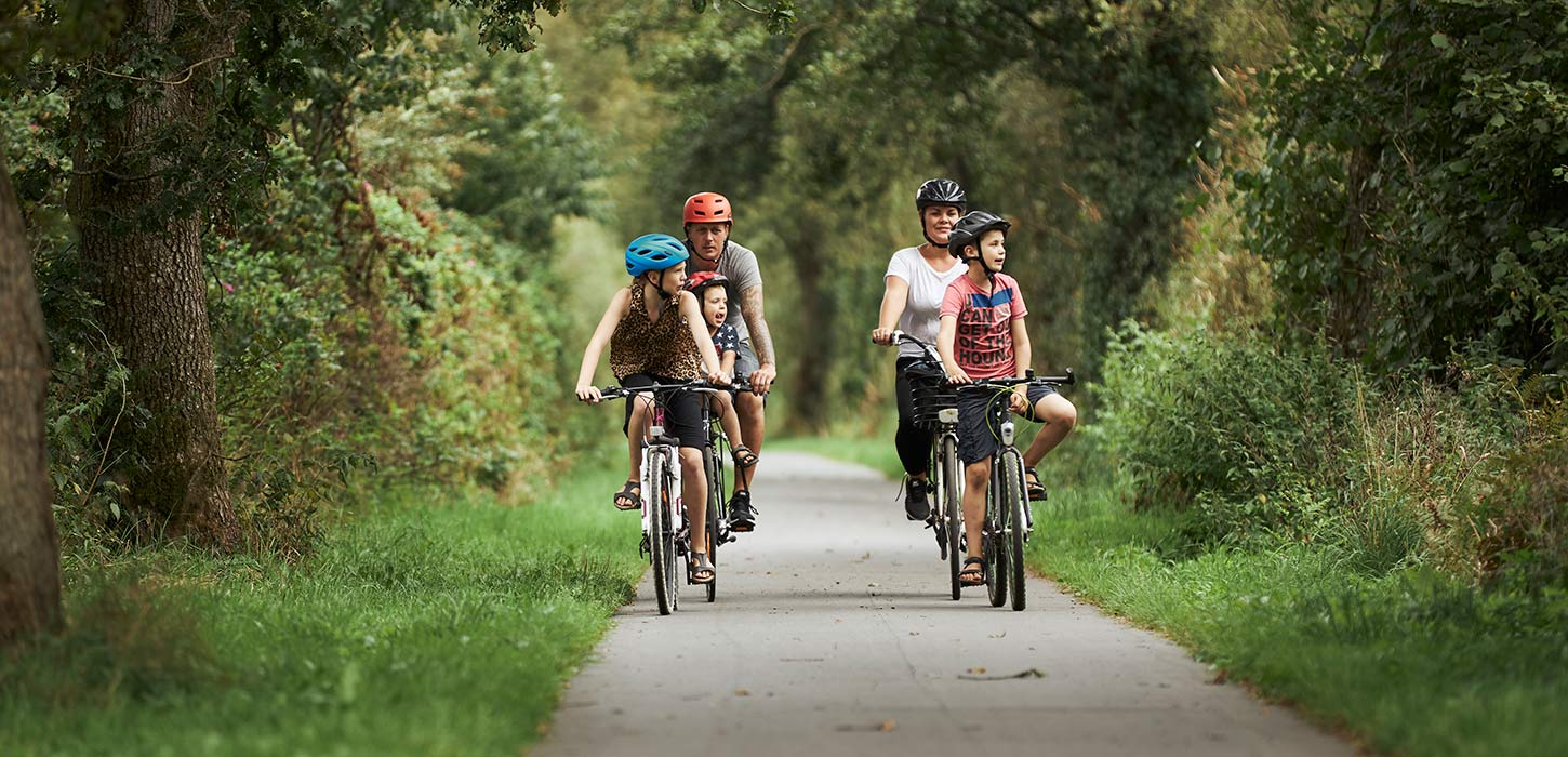 Eine Familie macht an einem Sommertag eine Radtour entlang des Bindeballestien