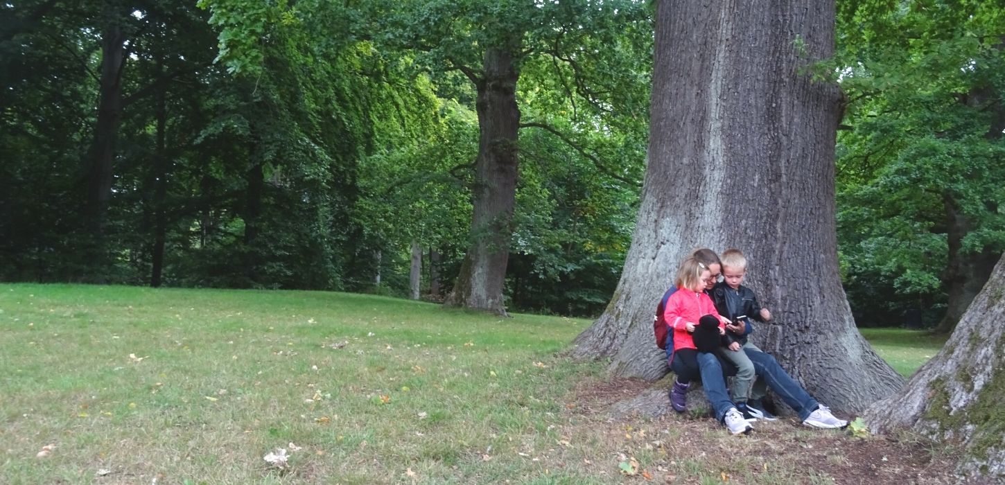 Mor med to børn på natureventyr i skoven