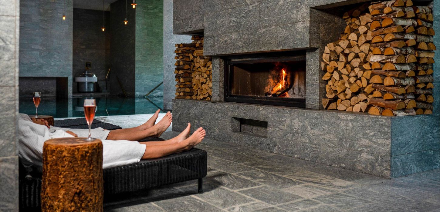 Paar vor dem Kamin mit Wein im Hotel Vejlefjord