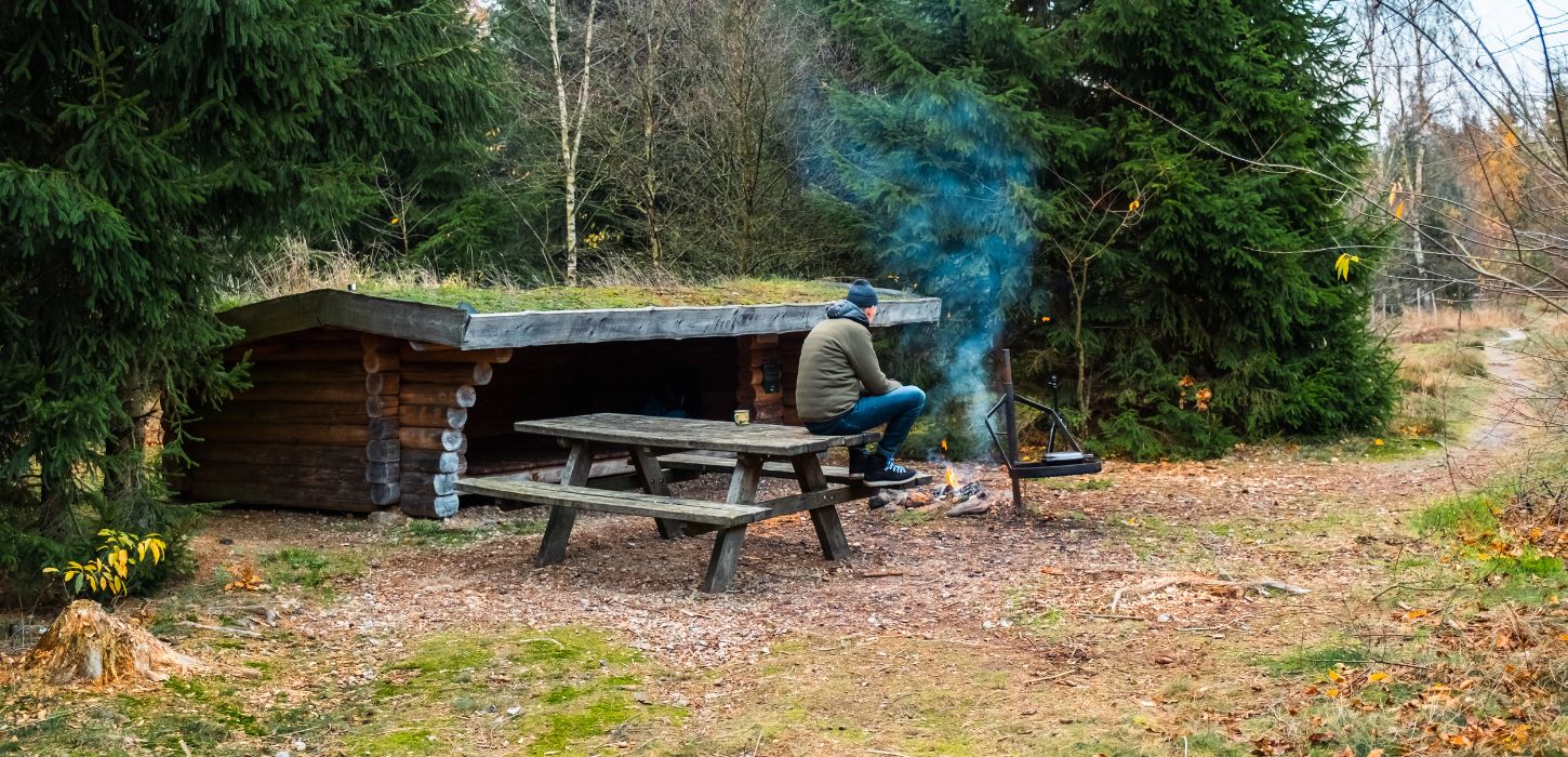 Eine Person ist auf einem Shelterausflug in Frederikshåb Plantage und macht ein Feuer