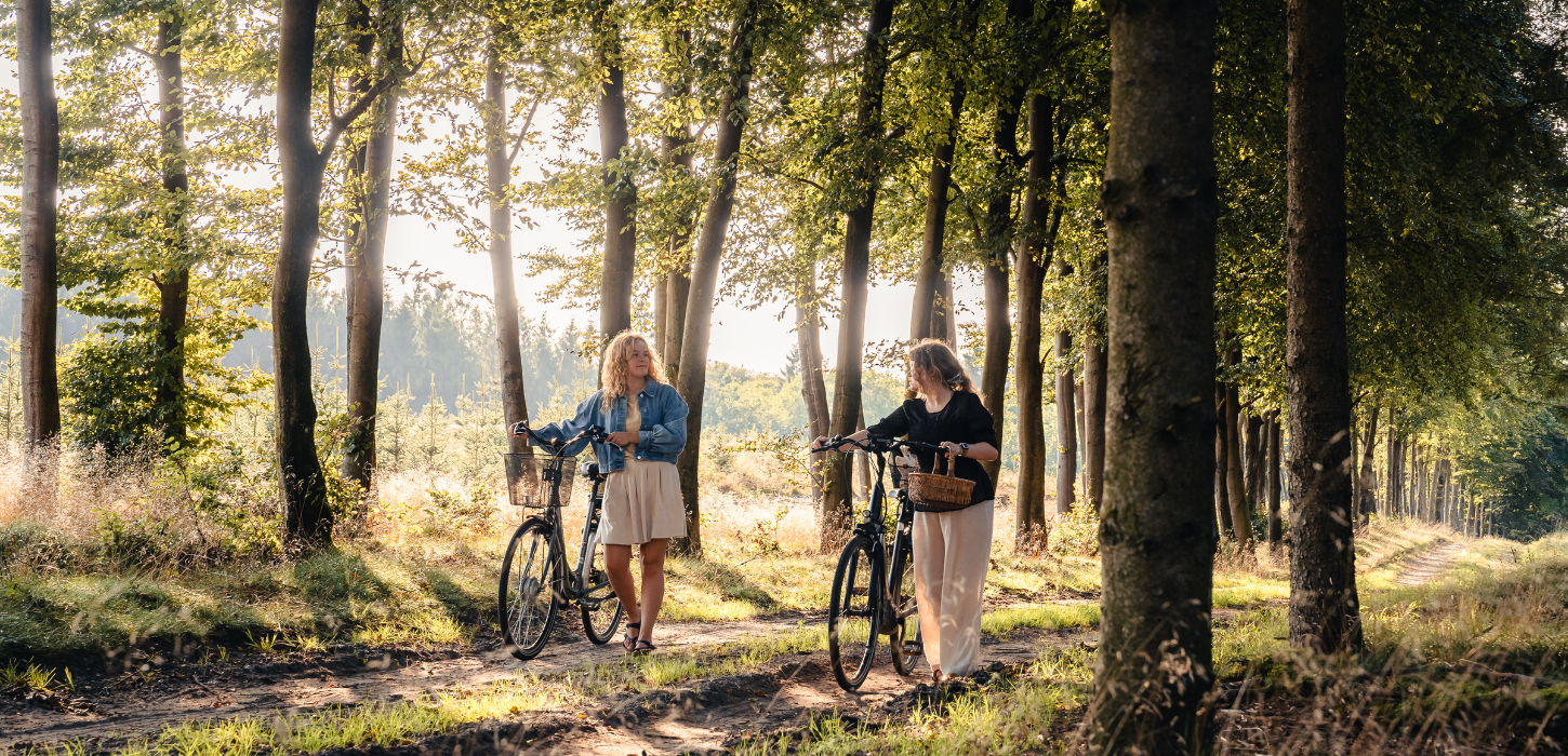 To kvinder på svampetur i skoven med cykler