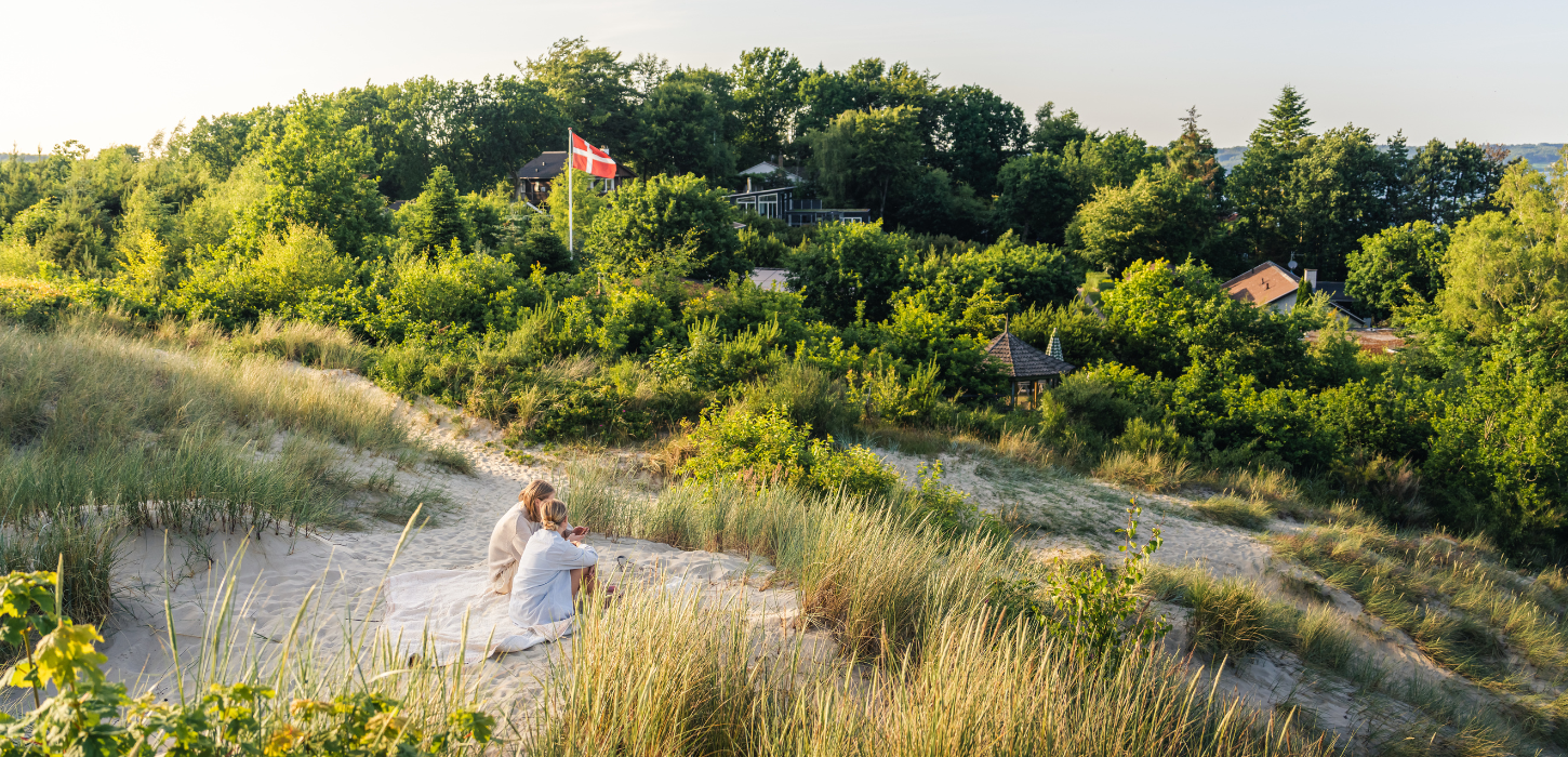 Kvinder sidder på sandklitten ved Hvidbjerg strand i Vejle