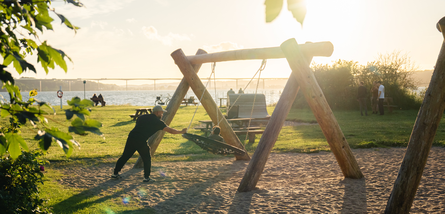 Vater und Kind schaukeln auf dem Spielplatz am Ibæk Strand