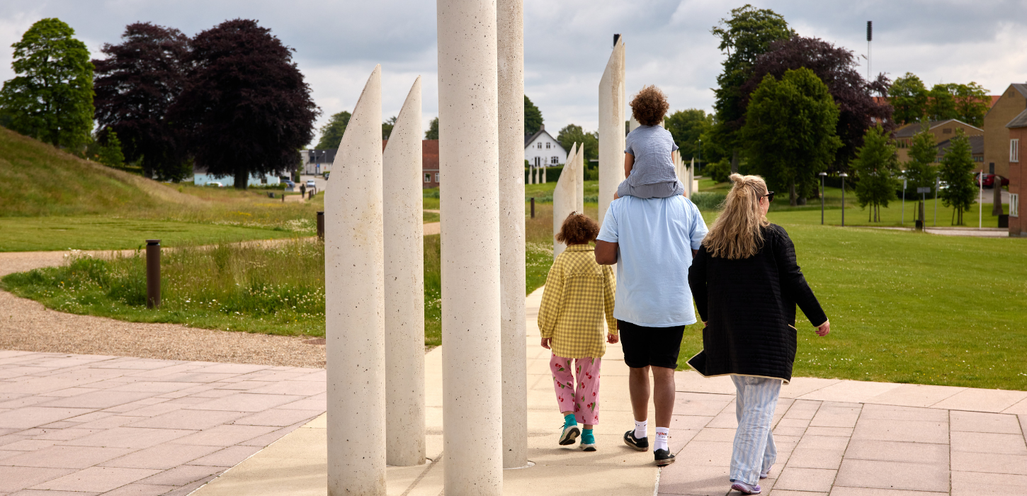 A family walks in the monument area in Jelling by the palisades