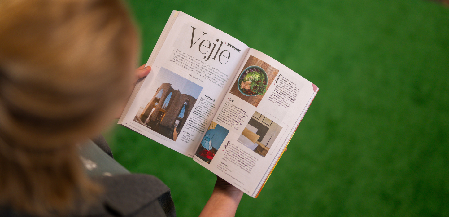 Woman looking through the destination guide “The Heart of Jutland 2026”