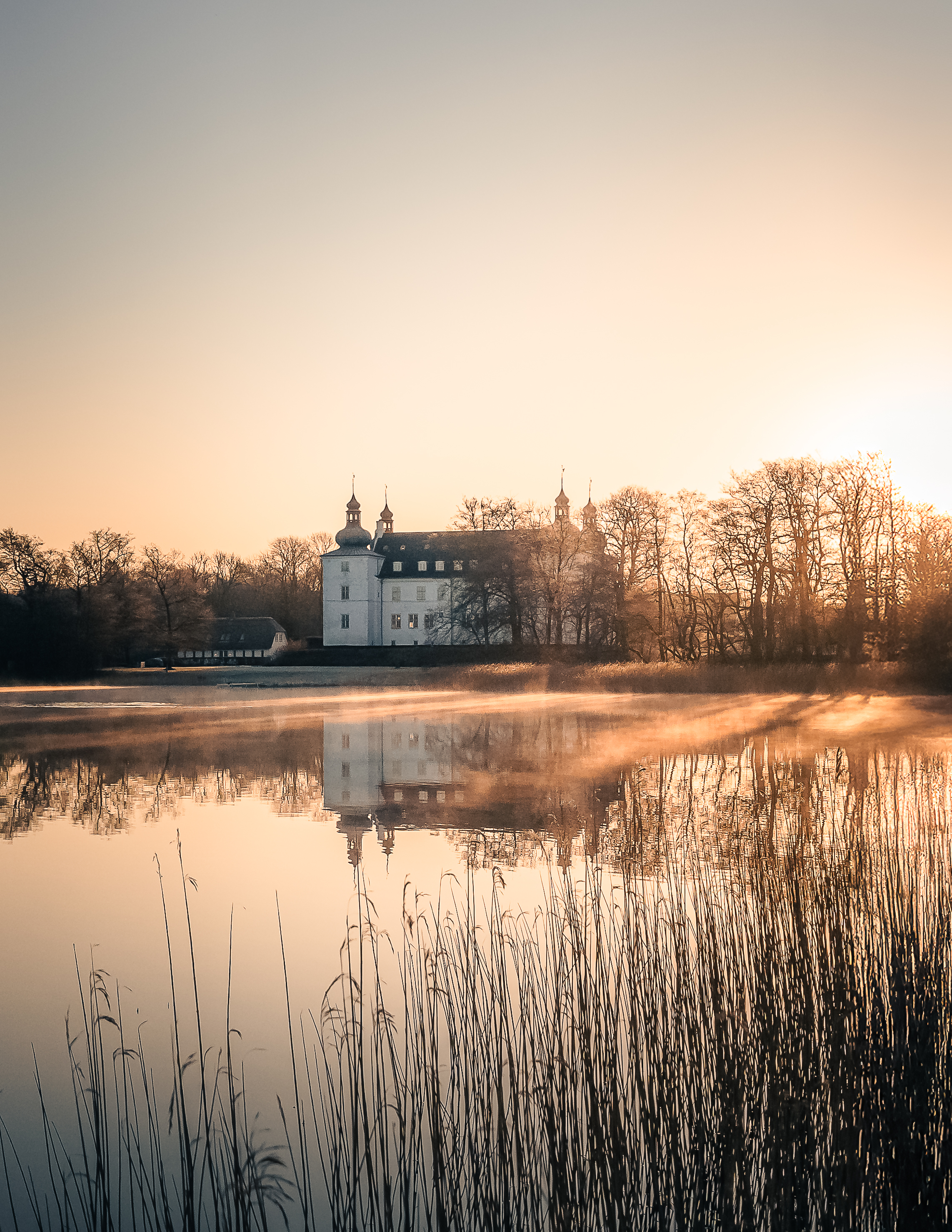 Morgensol over Engelsholm Slot og sø en vintermorgen