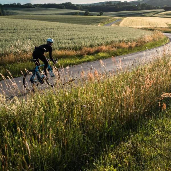 A person rides a racing bike on the country road along open fields in Vejle