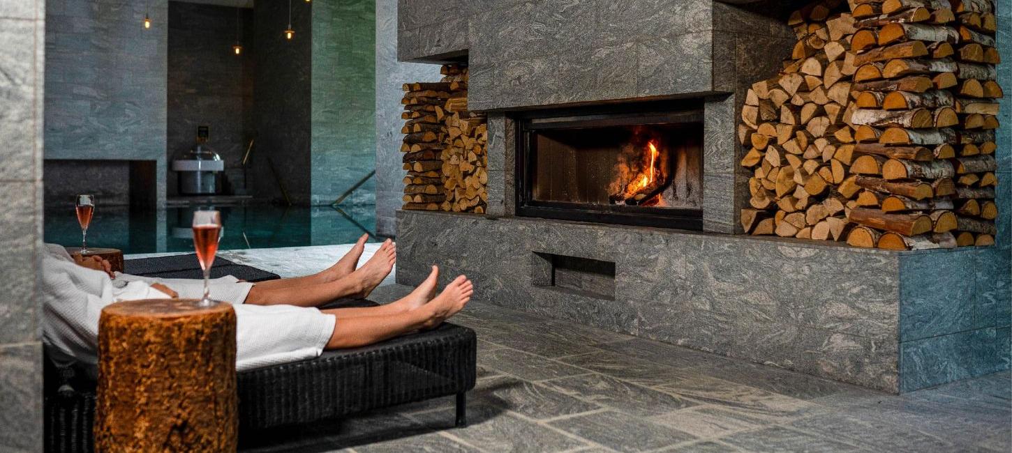 Couple in front of the fireplace with wine at Hotel Vejlefjord