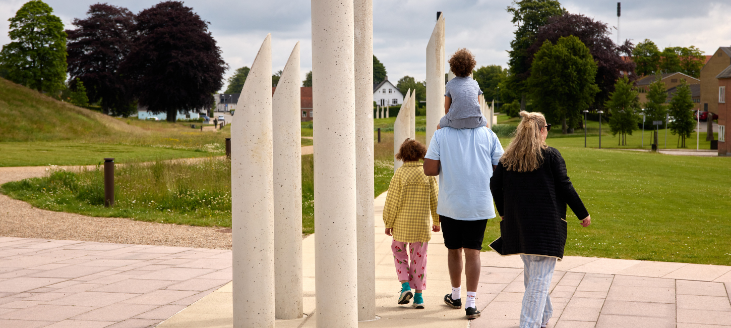 A family walks in the monument area in Jelling by the palisades