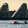 People in kayaks on Vejle Fjord with Bølgen (the Wave) in the background