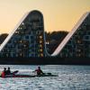 People in kayaks on Vejle Fjord with Bølgen (the Wave) in the background