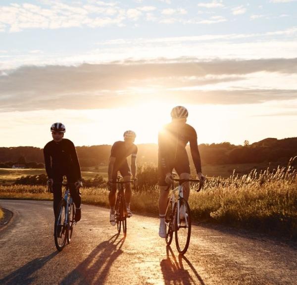 Cyklister på cykeltur ved Jelling med solnedgang