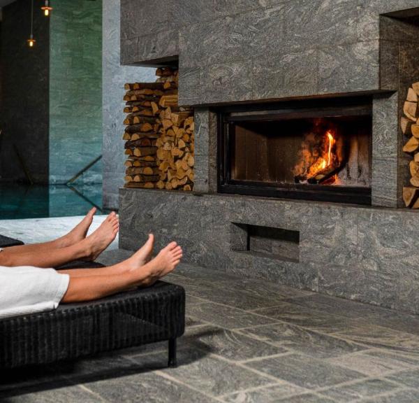 Couple in front of the fireplace with wine at Hotel Vejlefjord