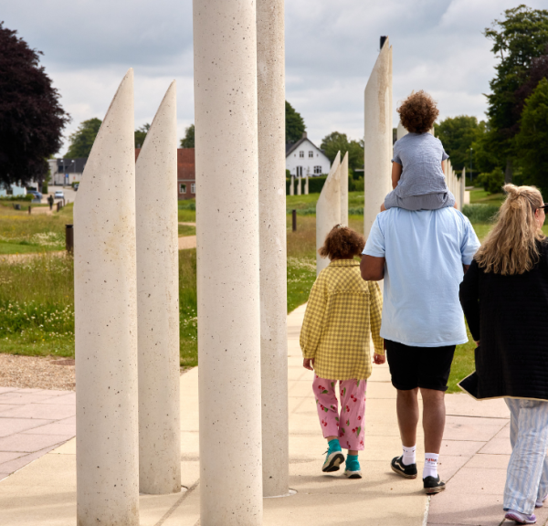 A family walks in the monument area in Jelling by the palisades