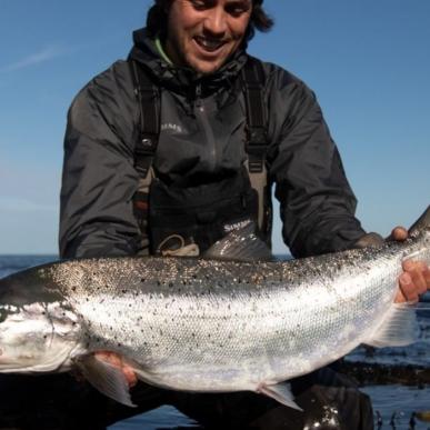 A fisherman with a sea trout in his hand at the shore