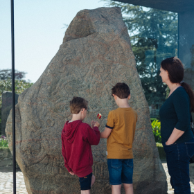 Family looks at one of the runestones at the monuments in Jelling