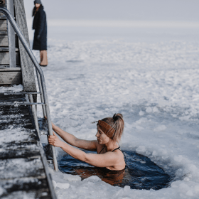 Woman bathing in winter by the fjord with ice on the fjord