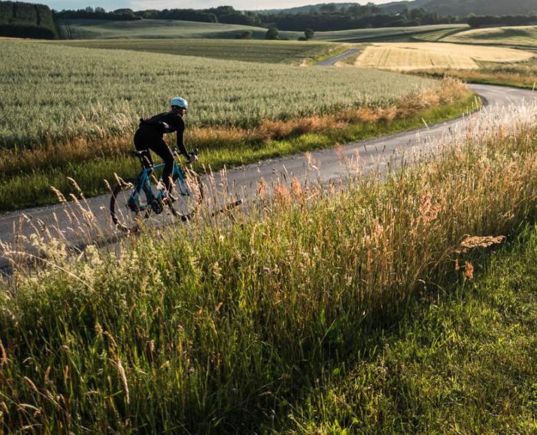 A person rides a racing bike on the country road along open fields in Vejle