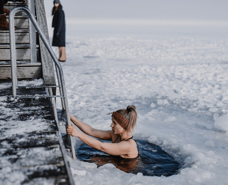 Woman bathing in winter by the fjord with ice on the fjord